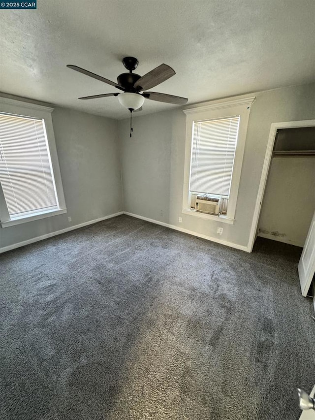 unfurnished bedroom with cooling unit, ceiling fan, dark carpet, and a textured ceiling