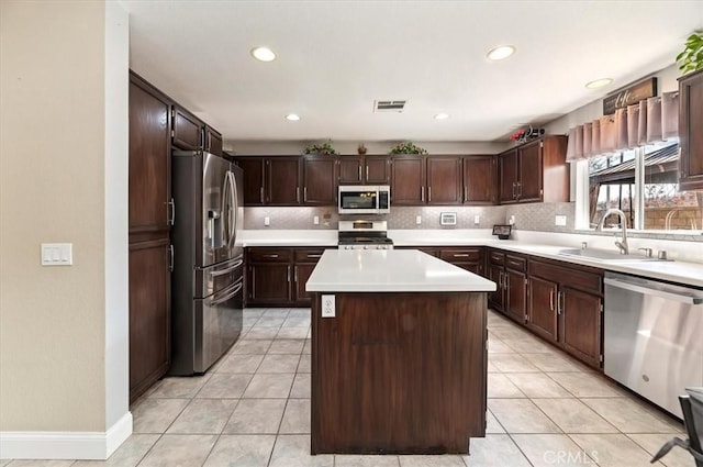 kitchen featuring light tile patterned flooring, sink, dark brown cabinets, appliances with stainless steel finishes, and a kitchen island