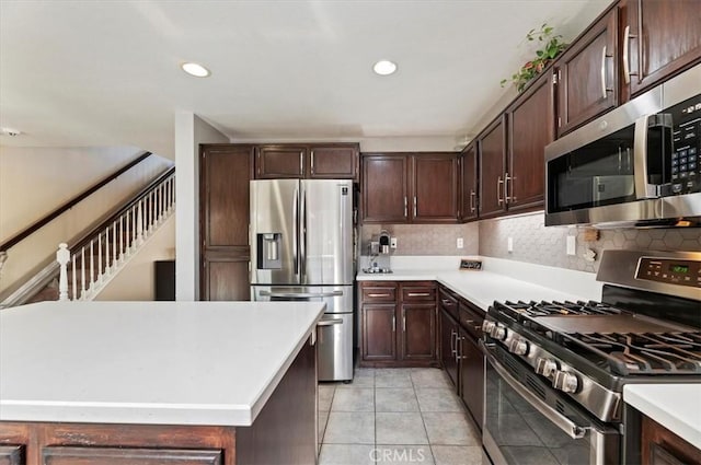 kitchen featuring stainless steel appliances, light tile patterned flooring, dark brown cabinets, and decorative backsplash