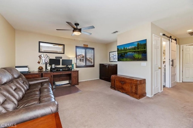 carpeted living room with a barn door and ceiling fan