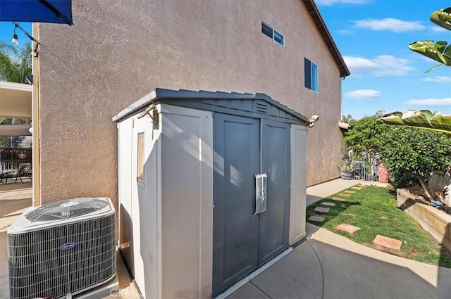 view of side of home featuring central AC and a storage shed