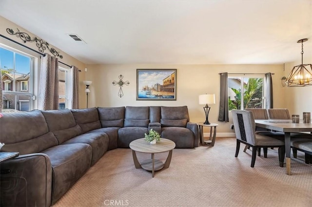 carpeted living room with a wealth of natural light and a chandelier