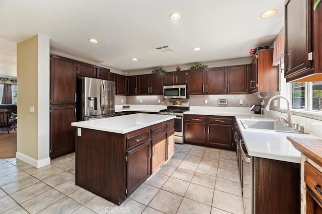 kitchen with dark brown cabinets, appliances with stainless steel finishes, sink, and a kitchen island