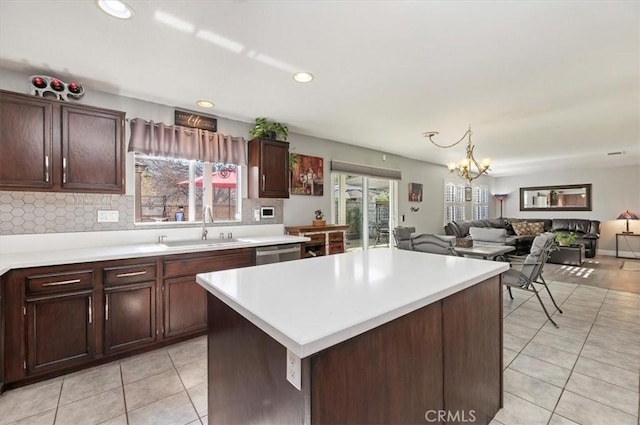 kitchen with a wealth of natural light, a kitchen island, sink, and stainless steel dishwasher