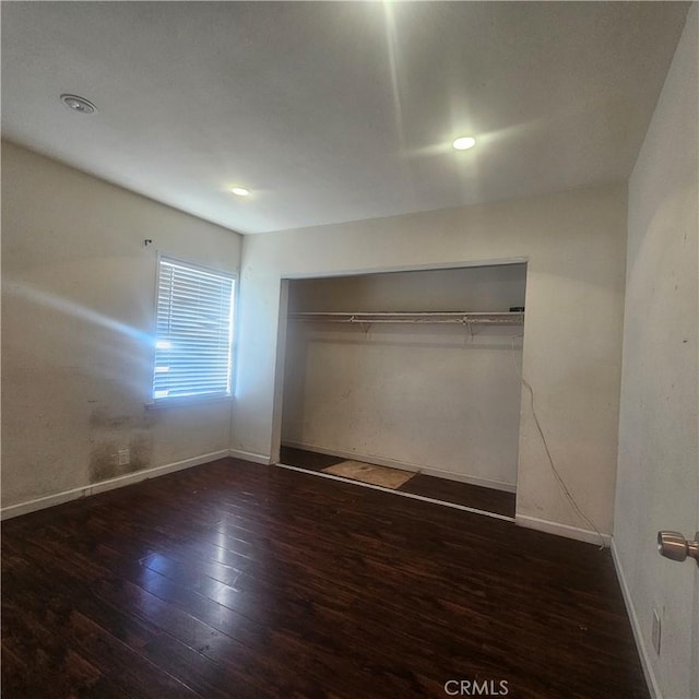 unfurnished bedroom featuring a closet and dark hardwood / wood-style flooring