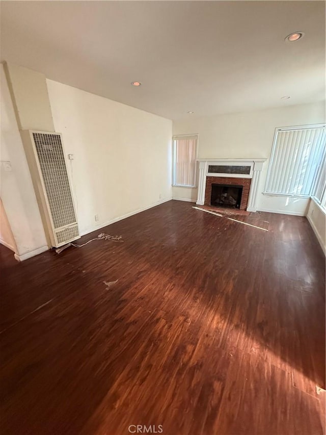 unfurnished living room with dark wood-type flooring and a fireplace