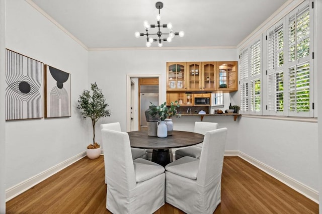 dining room featuring dark wood-type flooring, ornamental molding, and a chandelier