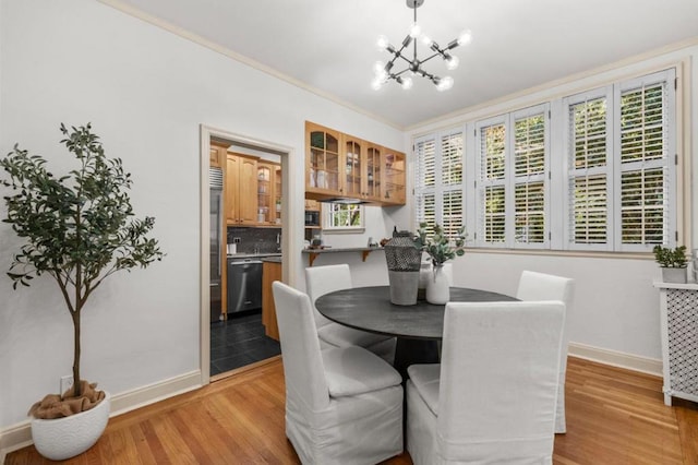 dining area with crown molding, a chandelier, and light hardwood / wood-style floors