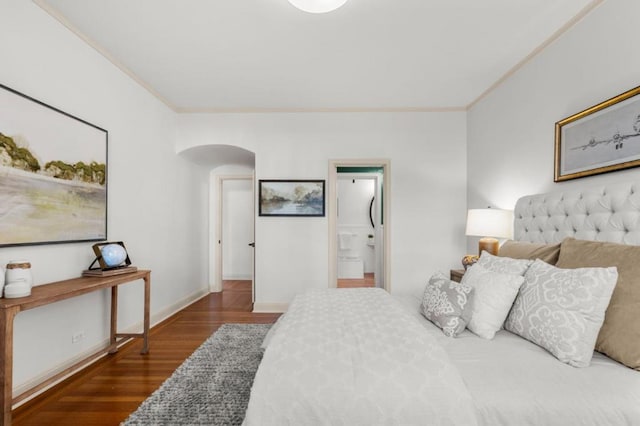 bedroom featuring dark hardwood / wood-style flooring, ornamental molding, and ensuite bathroom