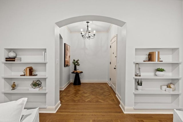 hall featuring crown molding, parquet flooring, and a notable chandelier