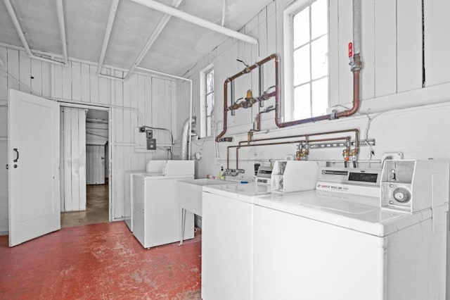 clothes washing area with sink, washer and clothes dryer, and wood walls