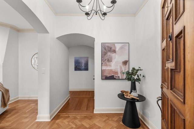 foyer entrance with an inviting chandelier, crown molding, and light parquet flooring