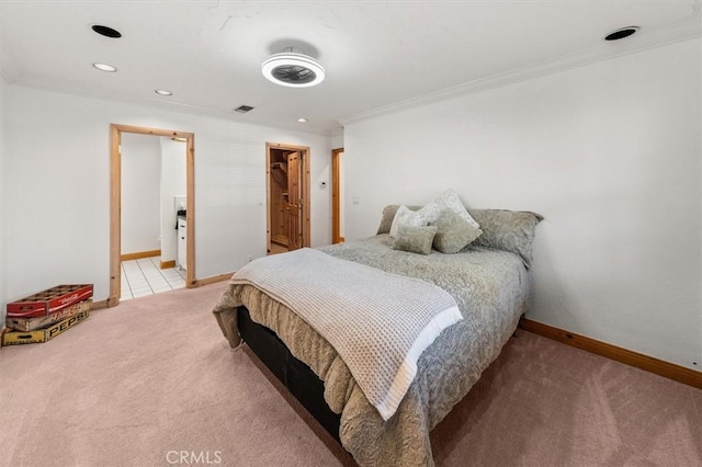 bedroom featuring a spacious closet, ensuite bath, light carpet, a closet, and crown molding