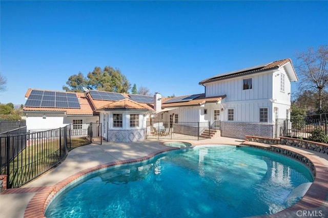 back of property with a fenced in pool, solar panels, and a patio