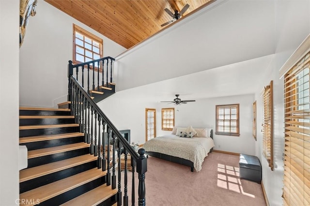 carpeted bedroom with wood ceiling, a towering ceiling, a ceiling fan, and baseboards