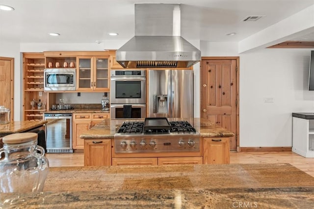 kitchen with light brown cabinetry, stone countertops, appliances with stainless steel finishes, and island range hood