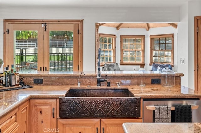 kitchen with sink, light brown cabinetry, dishwasher, and beamed ceiling