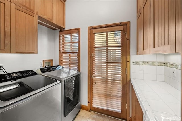 laundry area featuring light tile patterned floors, independent washer and dryer, and cabinets