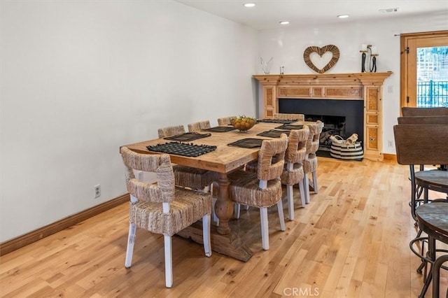 dining space with light wood-type flooring and a fireplace