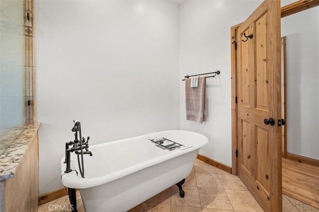 bathroom featuring a soaking tub and baseboards