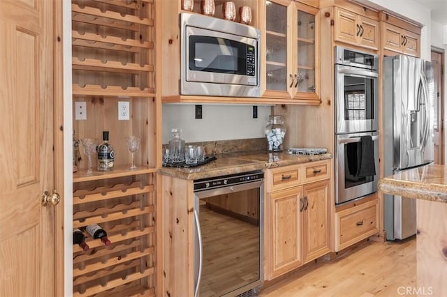 kitchen featuring stainless steel appliances, wine cooler, light brown cabinetry, light hardwood / wood-style flooring, and stone counters