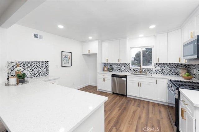 kitchen with backsplash, sink, appliances with stainless steel finishes, white cabinets, and dark hardwood / wood-style flooring