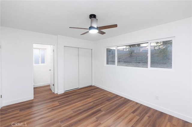 unfurnished bedroom featuring dark wood-type flooring, a closet, and ceiling fan