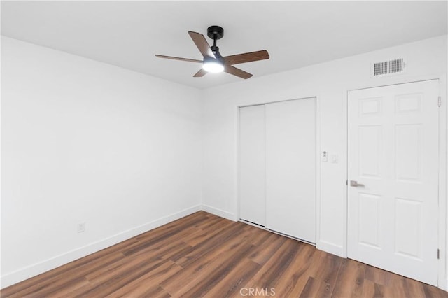 unfurnished bedroom with ceiling fan and dark wood-type flooring