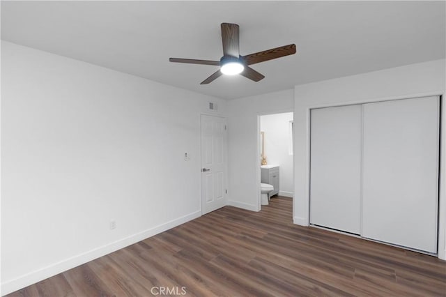 unfurnished bedroom featuring ceiling fan, ensuite bath, a closet, and dark hardwood / wood-style flooring