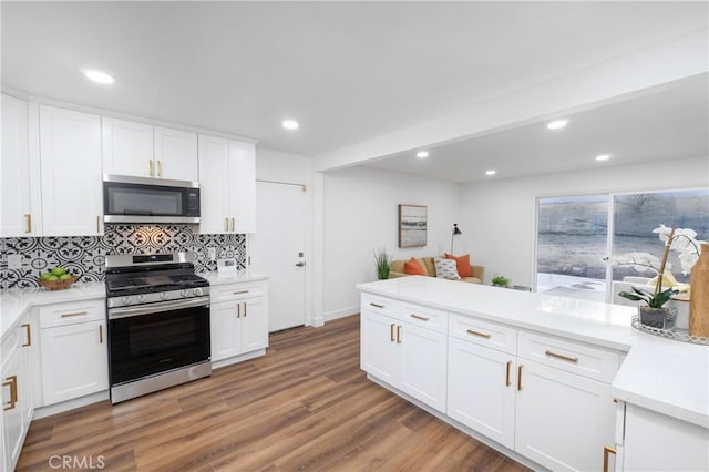 kitchen with backsplash, white cabinets, wood-type flooring, and appliances with stainless steel finishes