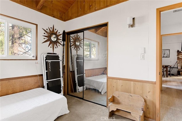 bedroom featuring vaulted ceiling, wood ceiling, wood walls, and a closet