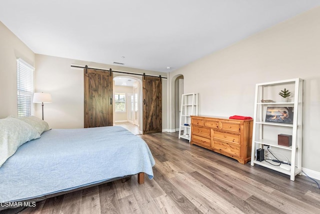 bedroom featuring multiple windows, wood-type flooring, and a barn door