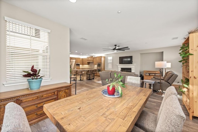 dining space with ceiling fan and light hardwood / wood-style flooring