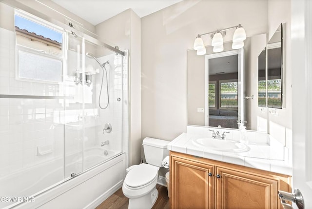 full bathroom with bath / shower combo with glass door, wood-type flooring, vanity, and toilet