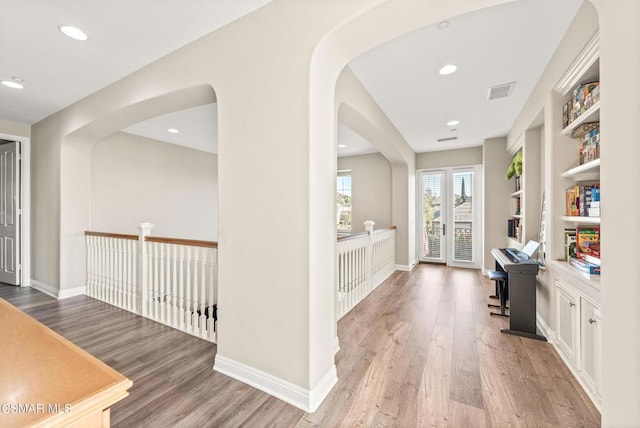 hallway with built in shelves, french doors, and hardwood / wood-style flooring