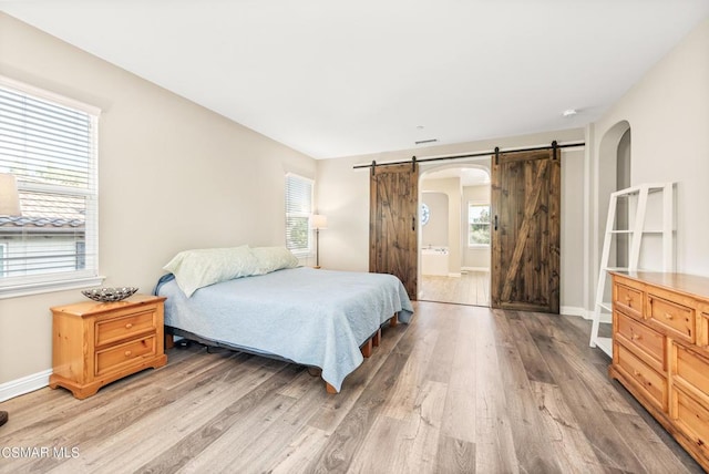 bedroom with hardwood / wood-style floors, a barn door, and ensuite bathroom