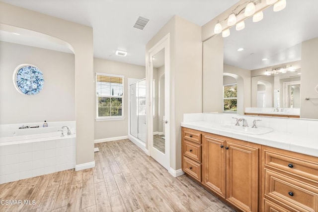 bathroom with hardwood / wood-style flooring, vanity, and shower with separate bathtub