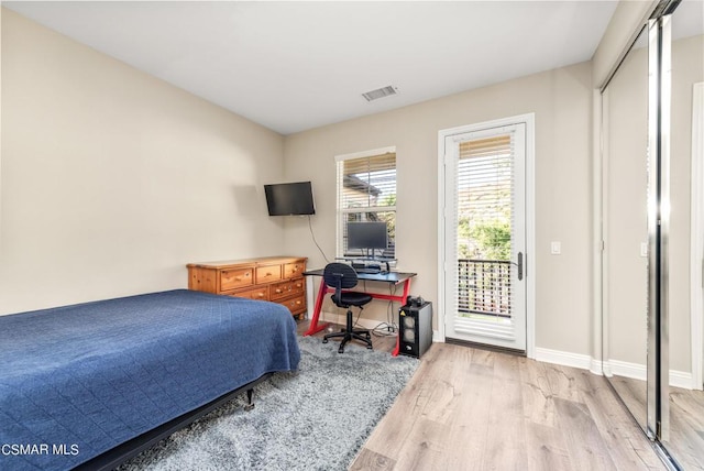 bedroom with access to outside, light hardwood / wood-style floors, and a closet