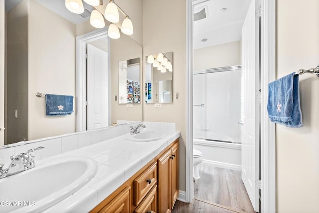 full bathroom with vanity, hardwood / wood-style floors, toilet, and combined bath / shower with glass door