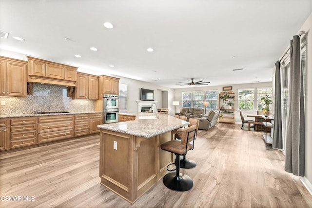 kitchen featuring sink, a breakfast bar area, tasteful backsplash, gas stovetop, and stainless steel double oven