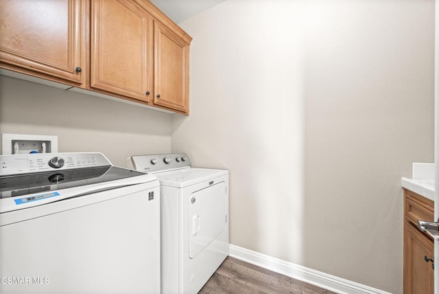 laundry area with cabinets, washer and dryer, and dark wood-type flooring