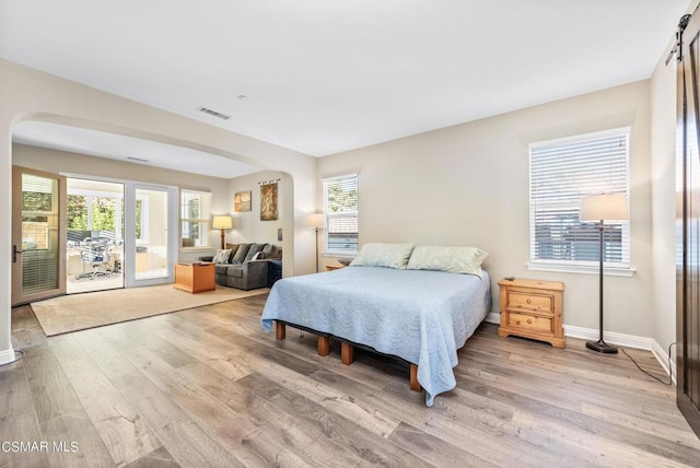 bedroom with multiple windows, access to outside, and light hardwood / wood-style flooring