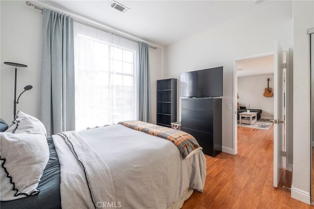 bedroom with black refrigerator and light hardwood / wood-style flooring