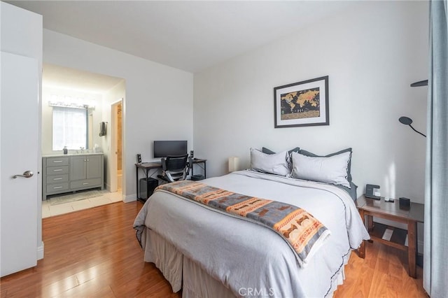 bedroom featuring light wood-type flooring and ensuite bath