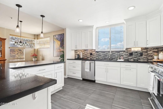 kitchen featuring white cabinetry, appliances with stainless steel finishes, backsplash, pendant lighting, and sink