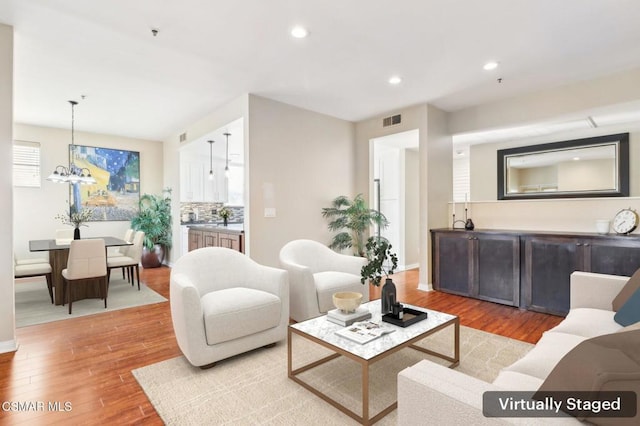 living room featuring a chandelier and light hardwood / wood-style flooring