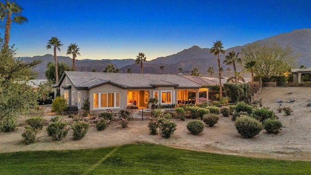 back house at dusk featuring a yard and a mountain view