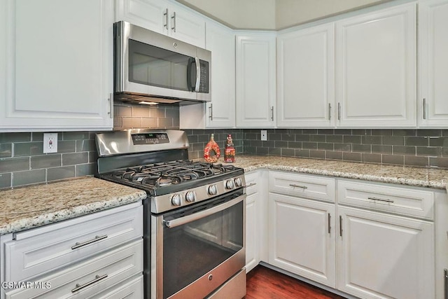 kitchen with light stone counters, appliances with stainless steel finishes, white cabinets, and tasteful backsplash