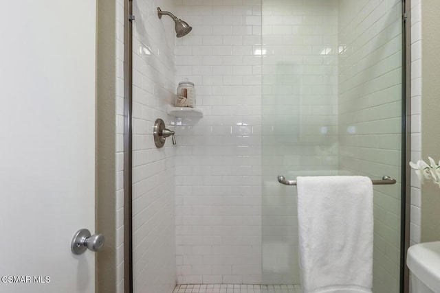 bathroom featuring toilet and a shower with door