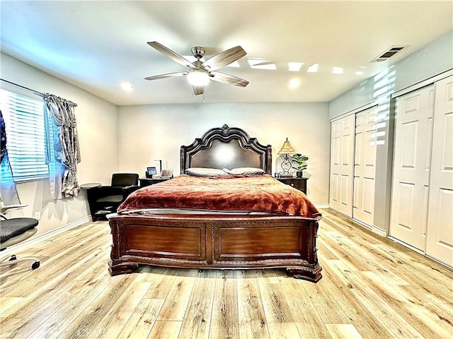 bedroom featuring ceiling fan, light hardwood / wood-style floors, and two closets